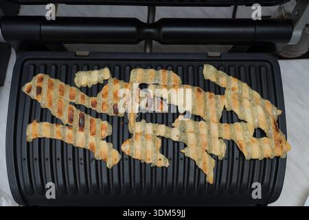 puff pastry cheese straws being cooked on a grill. These savory snacks are popular appetizers and are known for their flaky, cheesy, and crispy textur Stock Photo