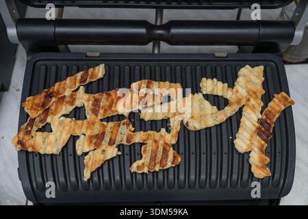 puff pastry cheese straws being cooked on a grill. These savory snacks are popular appetizers and are known for their flaky, cheesy, and crispy textur Stock Photo