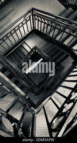 Top view of an industrial metal staircase with repeating geometric patterns and strong symmetry in black and white Stock Photo