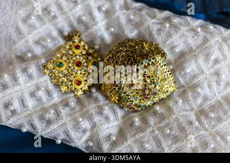 Elegant traditional gold jewelry with colorful gemstone ornament for wedding celebration. An intricate luxury design on white embroidered fabric backg Stock Photo
