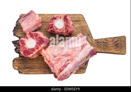Raw lamb oxtail pieces on wooden board with herbs and peppercorns over isolated background with copy space. Stock Photo
