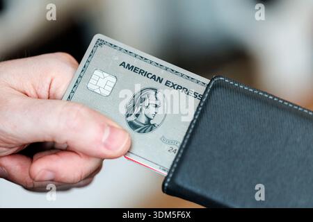 01 February 2026, Bavaria, Hohenschäftlarn: The American Express logo and lettering can be seen on an American Express Platinum Card, an exclusive premium metal credit card, which a young man pulls out of a wallet. American Express is a leading global financial services provider from the USA, known for its credit cards. The Amex Platinum is an exclusive, high-fee premium credit card for frequent travelers that offers extensive lifestyle and travel benefits. (symbol image, symbol photo, illustration, symbolic photo, illustrative photo, theme image, general image, theme photo, finance, Amex card Stock Photo