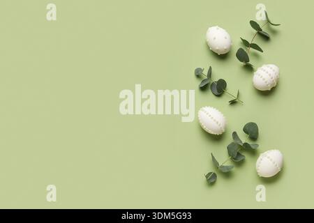 Easter eggs decorated with pearls and eucalyptus branches on green background Stock Photo