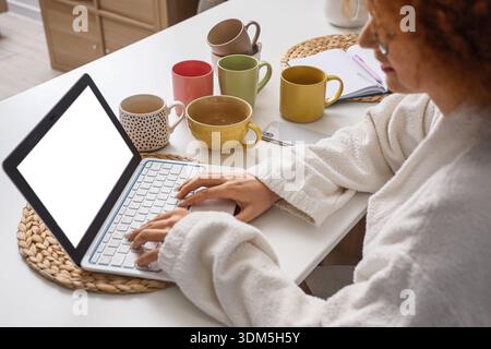 Female freelancer in bathrobe working with laptop at home Stock Photo