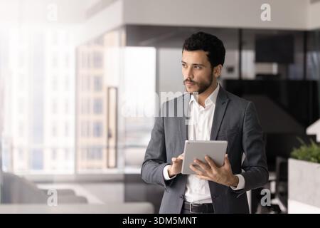 Young businessman standing in corporate office with digital tablet Stock Photo