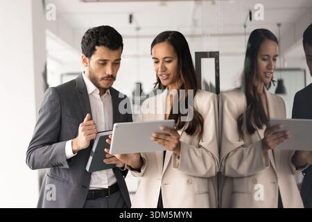 Two focused employees using tablet, working on joint task Stock Photo