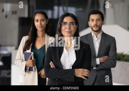 Mature businesslady boss and two multiethnic subordinates posing in office Stock Photo