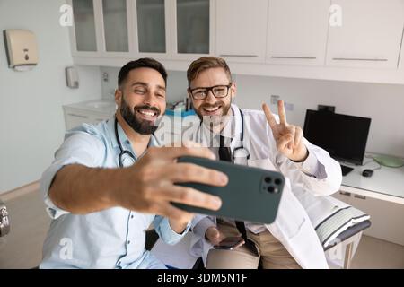 Two smiling young doctors posing for selfie in clinic office Stock Photo