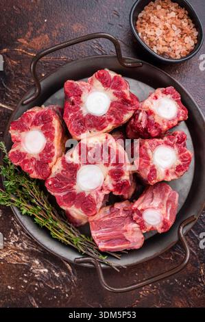 Raw Oxtail pieces in pan with fresh thyme, top view rustic food scene showing collagen rich beef for stock. Stock Photo