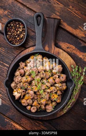 Fried chicken hearts with herbs and spices in skillet on wooden background perfect for rustic culinary photography Stock Photo