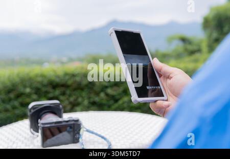 Male hand with smartphone and camera, he checking a photos before sharing on social media. Internet online concept Stock Photo
