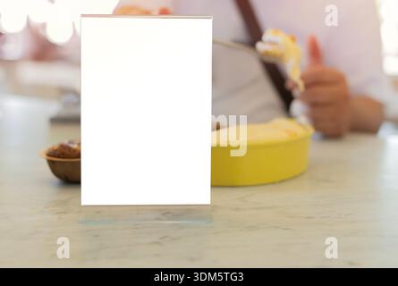 Blank frame on marble table with man and some sweets in restaurant setting and blurred behind. Copy space. Stock Photo