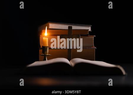 Dark, an antique candle cast its light on the old Bible, its flames flickering gently over the book on the table, symbolizing the enduring essence of Stock Photo