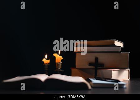 Dark, an antique candle cast its light on the old Bible, its flames flickering gently over the book on the table, symbolizing the enduring essence of Stock Photo