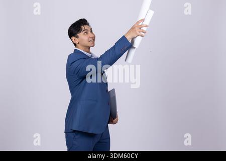 Architect in suit looking at building plan in studio Stock Photo
