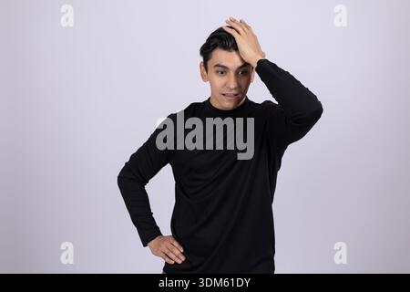 Man in black turtleneck touching his head in thought Stock Photo