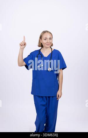 Female doctor in blue scrubs showing thumb up gesture Stock Photo