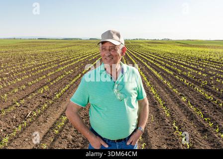Portrait of smiling senior farmer standing in corn field. Stock Photo