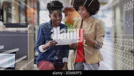 Reviewing printed document, women in denim and beige blazer viewing HUD data at office near laptop Stock Photo