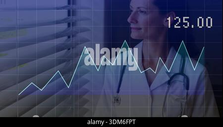 Studying female doctor gazing at window blinds with line-chart, white coat, stethoscope, copy space Stock Photo
