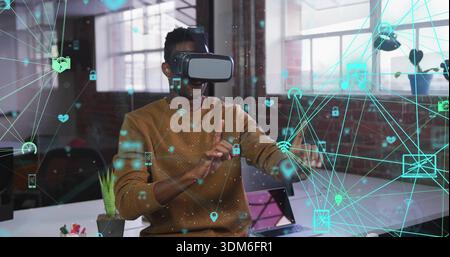 Using VR headset, man wearing brown sweater extending hands in loft, with holographic icons Stock Photo