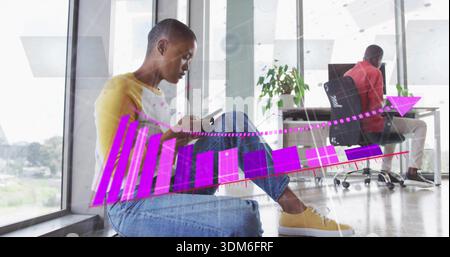 Checking phone, man on left windowsill wearing yellow top and jeans at office, with chart overlay Stock Photo