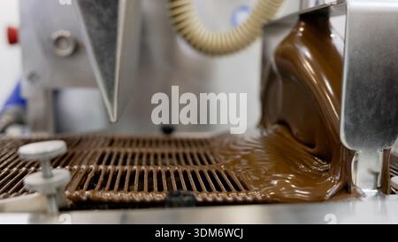 Liquid chocolate pouring on conveyor belt in factory Stock Photo