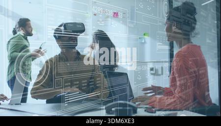 Interacting adult male wearing VR headset manipulating virtual UI at conference table, with laptops Stock Photo