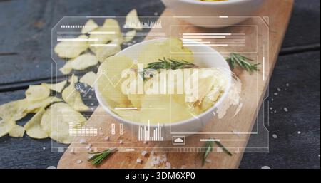 Displaying white ceramic bowl holding pale yellow potato scoops on cutting board with chips and HUD Stock Photo