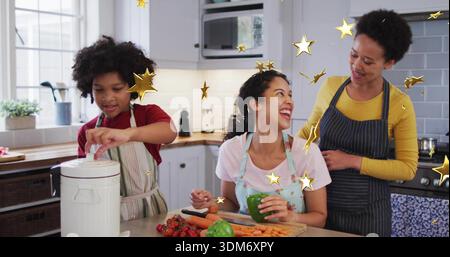 Laughing family preparing vegetables in home kitchen, wearing aprons, using cutting board, knife Stock Photo