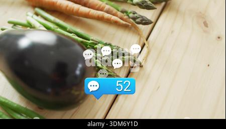Displaying eggplant asparagus carrots on light wood table, with white speech icons and blue chat 52 Stock Photo