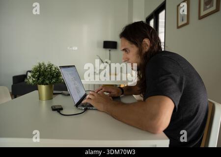 Young man typing on laptop, working from home Stock Photo