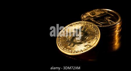 Bitcoin coin isolated on black background. Stack of gold coins with Bitcoin coin in front of it. Golden Bitcoin, cryptocurrency. Stock Photo
