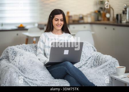Young woman smiling, working on laptop from home Stock Photo