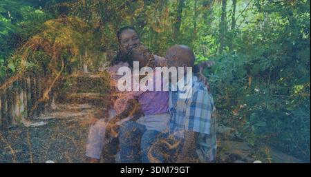 Sitting senior woman, child, senior man sharing moment on bench in wooded park, golden overlay Stock Photo