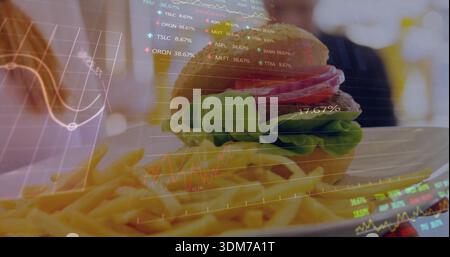 Featuring plated sesame-bun burger and fries sitting on white plate at cafe, with financial overlay Stock Photo