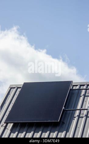 Solar panel installed on a private house metal roof under a blue sky. Stock Photo