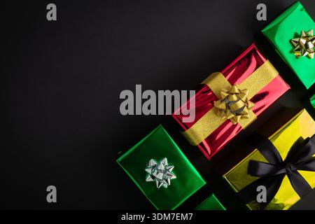 Top view photo of four stylish colorful gift boxes with golden and black ribbon bows on isolated black background with copyspace Stock Photo