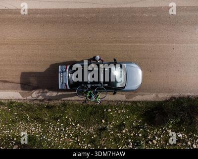 High angle aerial drone shot looking straight down at a grey Toyota Corolla Cross Hybrid vehicle parked on the side of a road. Stock Photo
