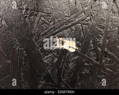9mm Bullet Hole in Black Painted Oriented Strand Board Wood Panel Texture Detailed Close-up of Impact Damage in Construction Material. Stock Photo