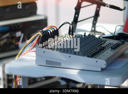 Close-up of an audio mixing console with multiple dials, sliders, and connected cables, used for managing sound in live events, recording sessions, or Stock Photo