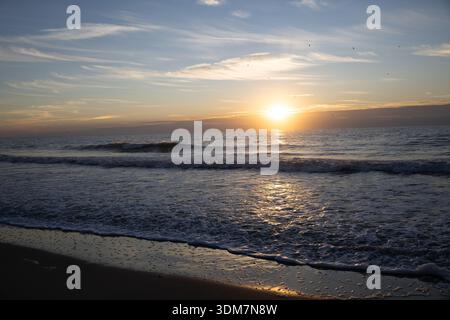 Sunrise over the Atlantic Ocean with calm waves and soft morning light reflecting across the water, creating a tranquil coastal seascape. Stock Photo