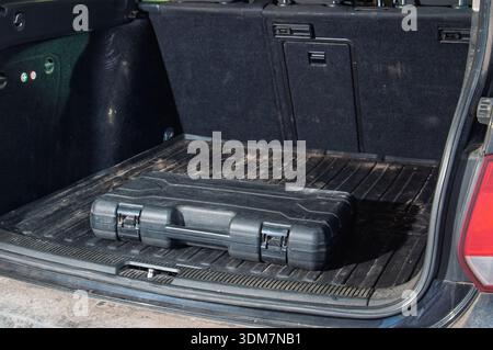 A durable black case sits on a ribbed rubber liner inside the cargo area of a vehicle, ready for transport Stock Photo