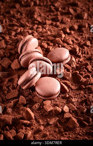 Sweet chocolate macaroons with chocolate cream and cocoa. Chocolate macaroons on cocoa background. Stock Photo