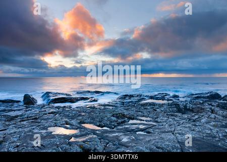 Rain clouds over the open water of the blue Atlantic at sunset with orange coloured cloudy sky, northwest coast of Scotland Stock Photo