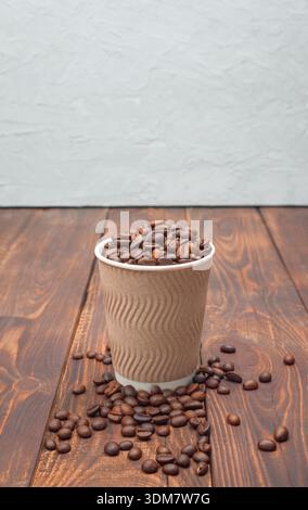 Mockup coffee in a disposable cup on a wooden table and coffee grains, dark background. Coffee background. Stock Photo