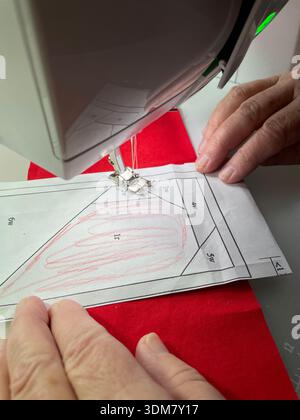 Precision foundation paper piecing (FPP) in action: sewing fabric pieces onto a marked paper template for accurate quilting results.Photo by Willy Matheisl Stock Photo