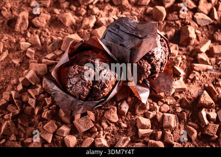 Tasty chocolate muffins on chopped dark chocolate and cocoa. Muffins on chocolate and cocoa background. Stock Photo