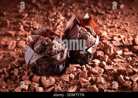 Sweet chocolate muffins on chopped dark chocolate and cocoa. Muffins on chocolate and cocoa background. Stock Photo