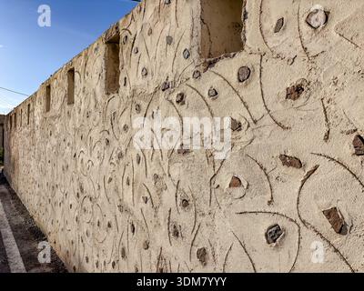 Textured stucco wall detail in Fira (Thira), Santorini, Greece. Features decorative incised patterns and embedded volcanic stones, typical of Cycladic Stock Photo